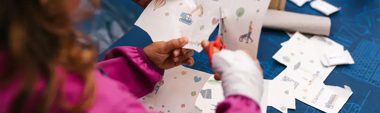 Basten mit Kindern mit Schere und Vorlagen an einem Kreativstand beim Stadtteilfest.