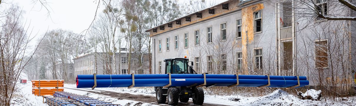 Ein Baustellenfahrzeug transportiert Rohre für den Leitungsbau in Krampnitz 