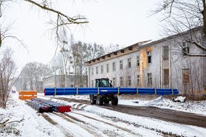 Ein Baustellenfahrzeug transportiert Rohre für den Leitungsbau in Krampnitz 