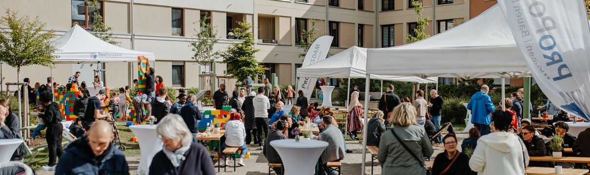 Innenhof eines Wohnhauskomplexes mit vielen Menschen im Gespräch miteinander