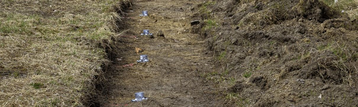 Blick auf Wiesenstreifen mit Zaunpfahlfundamenten. Eindruck der Baumaßnahmen zur Errichtung des Katzenschutzzaunes im Stadtquartier Krampnitz. 