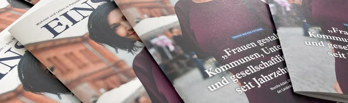 Mehrere Magazine liegen aufgefächert auf einem Tisch. Auf dem Titelbild ist eine Frau mit dunklen Haaren und einem lilafarbenen Kleid zu sehen.