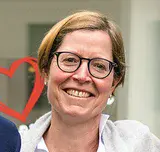 Zu sehen sind sechs Frauen, die nebeneinander stehen, die Arme umeinandergelegt haben und in die Kamera lächeln.
