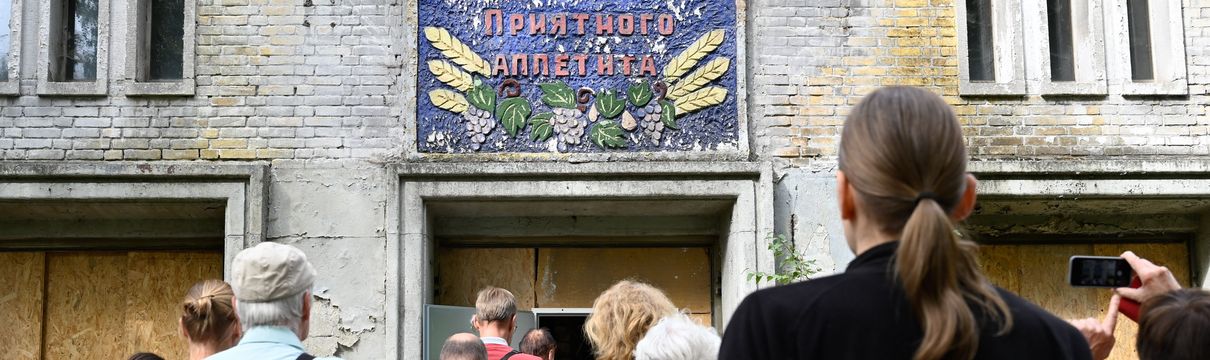 Menschen stehen vor einem alten Gebäude in Krampnitz.