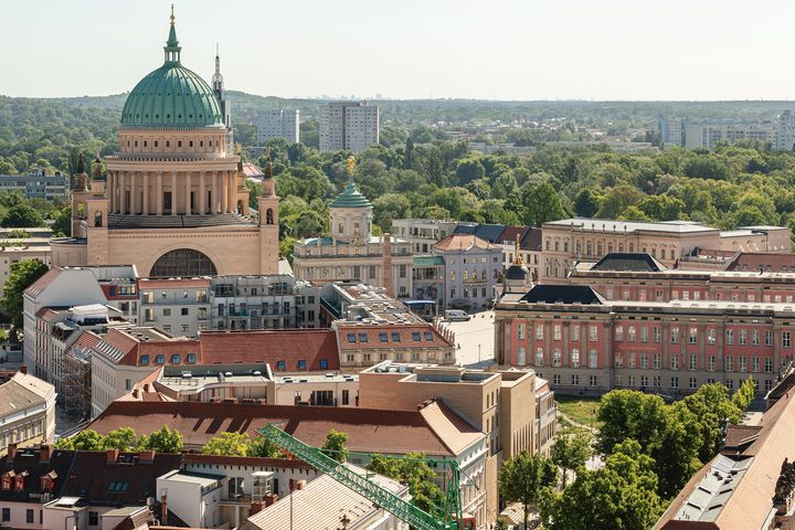 Blick auf den Alten Markt in Potsdam mit der Kuppel der Nikolaikirche, dem Brandenburger Landtag und umliegenden historischen Gebäuden, umgeben von Grünflächen
