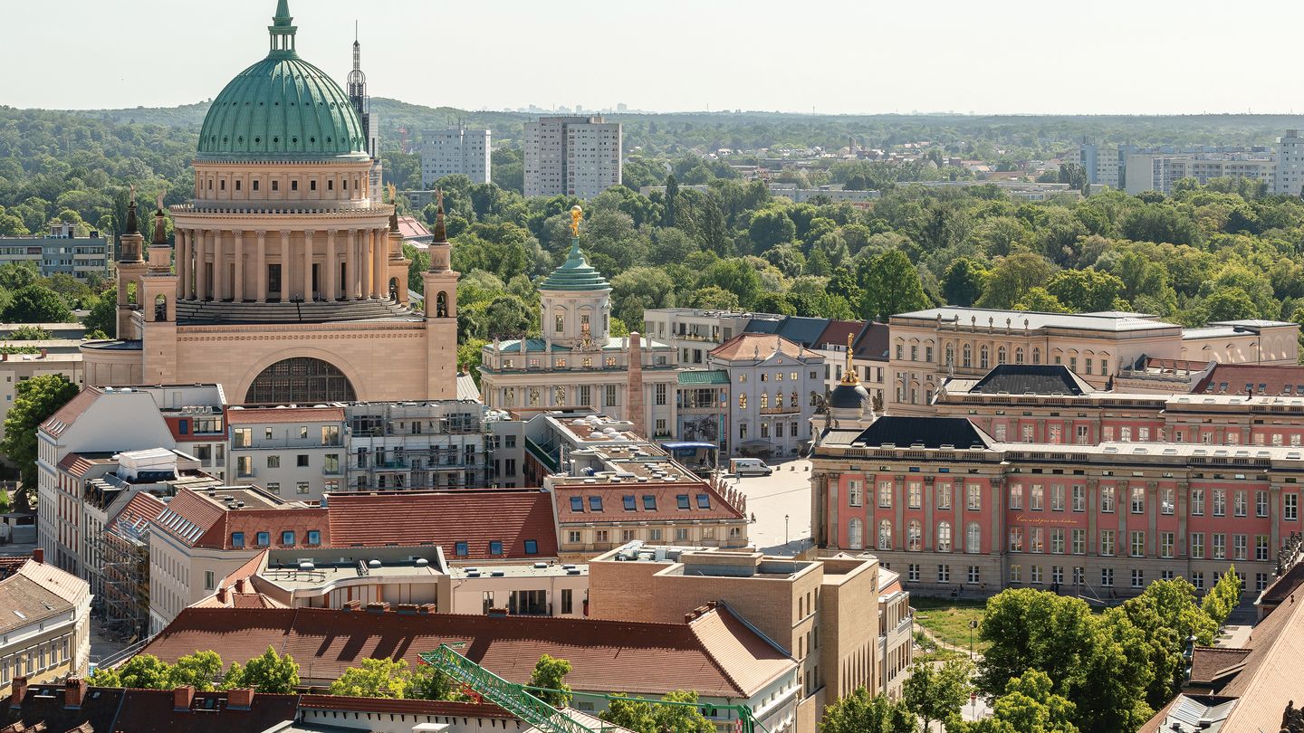Blick auf den Alten Markt in Potsdam mit der Kuppel der Nikolaikirche, dem Brandenburger Landtag und umliegenden historischen Gebäuden, umgeben von Grünflächen