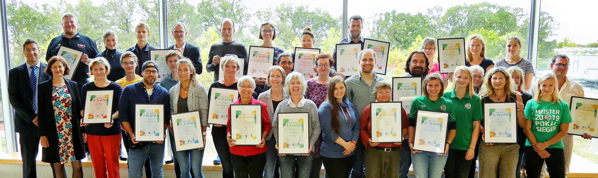 Ein Gruppenbild mit Personen, die Urkunden in den Händen halten.