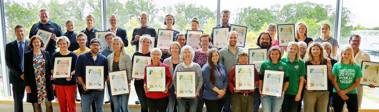 Ein Gruppenbild mit Personen, die Urkunden in den Händen halten.