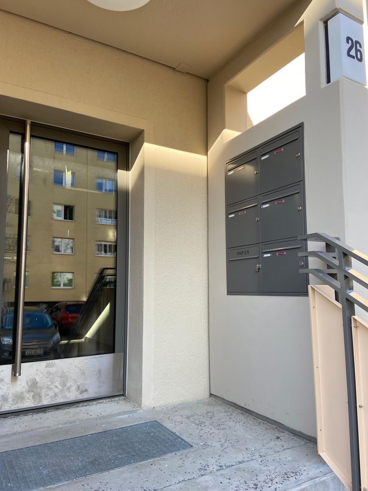 Hauseingang im Willy-A.-Kleinau-Weg mit neuer Briefkastenanlage an der Wand, Glastür mit Spiegelung und Treppengeländer im Eingangsbereich.