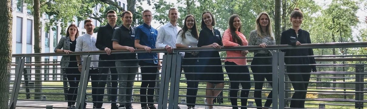 Gruppenbild junger Leute, die nebeneinander am Geländer eine Brücke stehen.