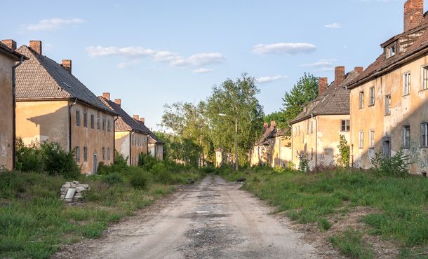 Ein breiter Sandweg führt durch die links und rechts des Weges stehenden, ehemaligen Offiziershäuser des wild von Bäumen und Sträuchern überwucherten Bergviertels.