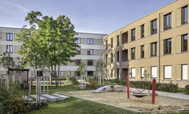Grüner Innenhof mit kleinem Spielplatz umgeben von Wohhäusern