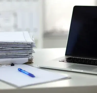 Ein Stapel Papier und ein Laptop