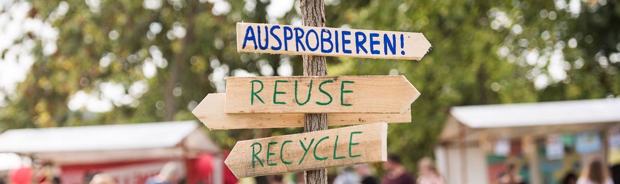 Umweltfest_(c)_Ingo Kniest Wegweiser aus Holz mit den Aufschriften 'Ausprobieren', 'Reuse' und 'Recycle'.