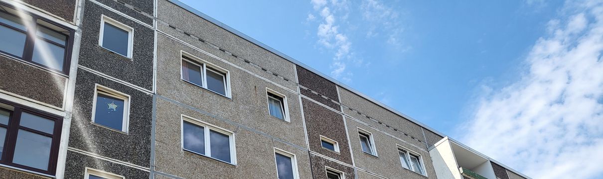 Graues Plattenbaugebäude und blauer Himmel