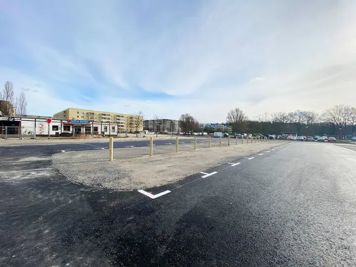 Neu asphaltierte Straße und Markierungen auf einem Parkplatz. Blauer Himmel im Hintergrund