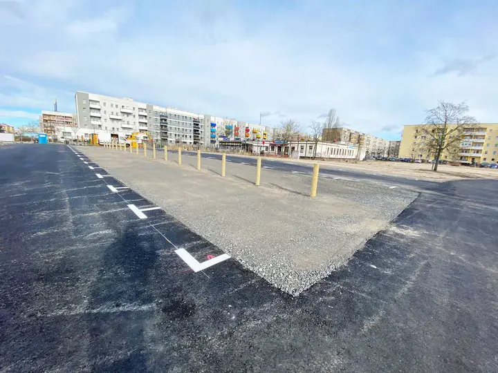 Neu asphaltierte Straße und Markierungen auf einem Parkplatz. Blauer Himmel im Hintergrund
