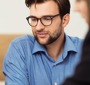 Eine Frau und ein Mann schauen gemeinsam mit einer Beraterin auf etwas auf einem Tisch