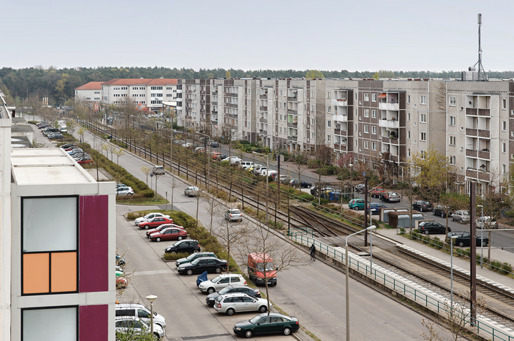 Blick vom Hausdach auf eine große Straße, viele parkende Autos 