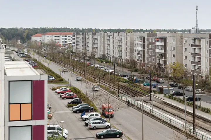 Blick vom Hausdach auf eine große Straße, viele parkende Autos 