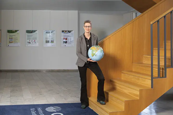Prof. Dr. Susanne Buiter, Wissenschaftliche Vorständin des GFZ Helmholtz-Zentrum für Geoforschung Eine Frau mit grauem Blazer, die einen Globus in der Hand hält