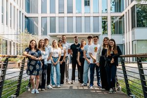 Junge Menschen stehen vor einem Gebäude mit Glasfassade.