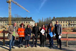 Sieben Menschen, darunter Oberbürgermeister Mike Schubert, Baubeigeordneter Bernd Rubelt und Entwicklungsträger-Potsdam-Geschäftsführer Bert Nicke, stehen vor einer Baustelle in Krampnitz.