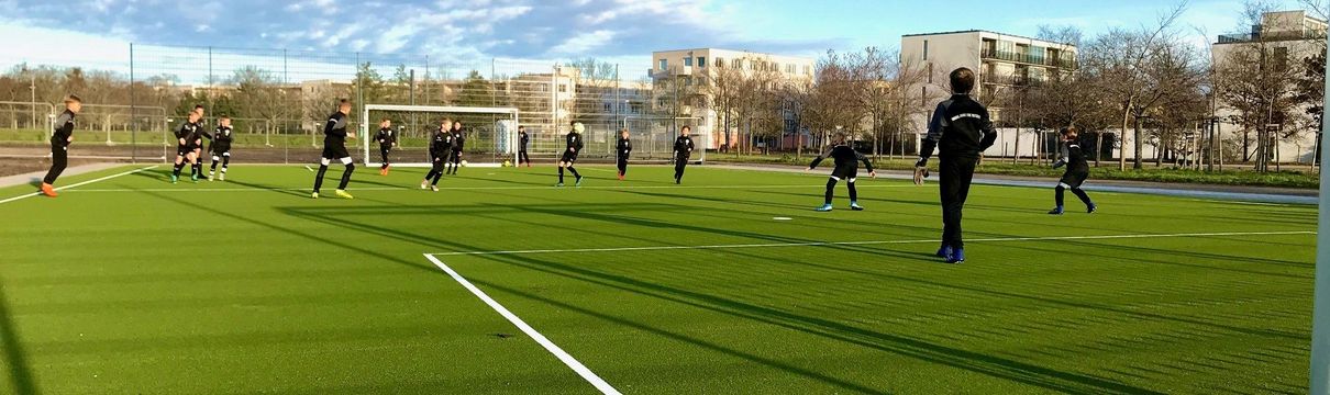 Das Bild zeigt den neuen Kunstrasenplatz im Volkspark, auf dem gerade Fußball gespielt wird.