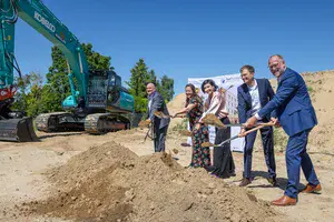 Spatenstich für neuen Wohncampus in Potsdam-Bornstedt mit Beteiligten vor Bagger und Baufläche