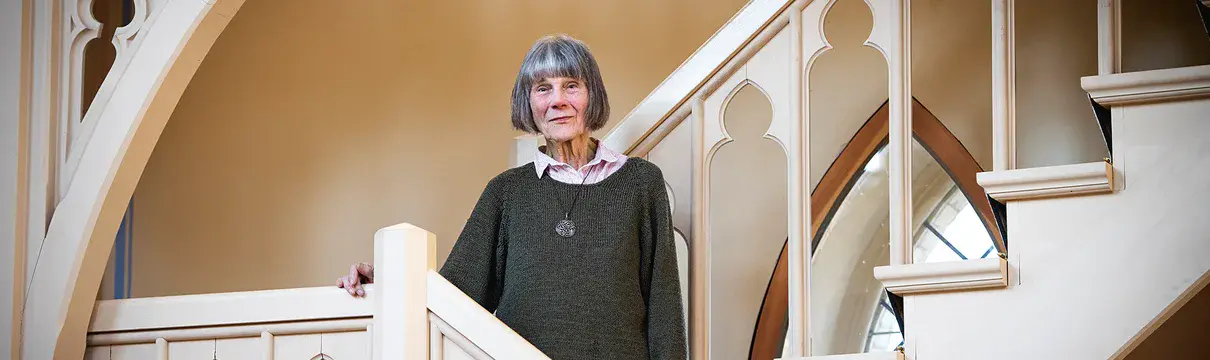 Eine ältere Frau steht auf einer Treppe in einer Kirche 