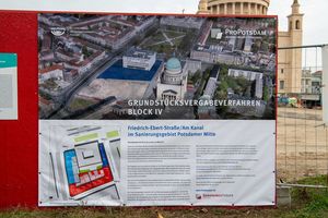 Ein Banner mit der Aufschrift "Grundstücksvergabeverfahren Block IV" und dem Logo der ProPotsdam hängt an einem Bauzaun. Im Hintergrund ist ein historisches Kirchengebäude zu sehen.