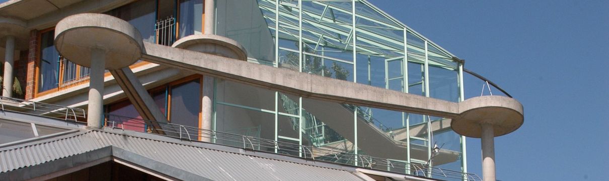 Auschnitt des Terrassenhauses mit einer Glasfront und runden Betonteilen.