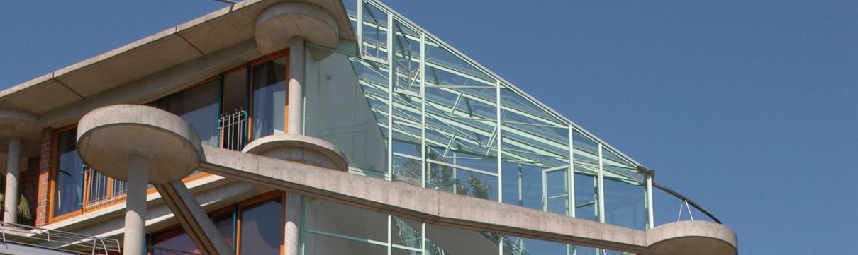 Auschnitt des Terrassenhauses mit einer Glasfront und runden Betonteilen.