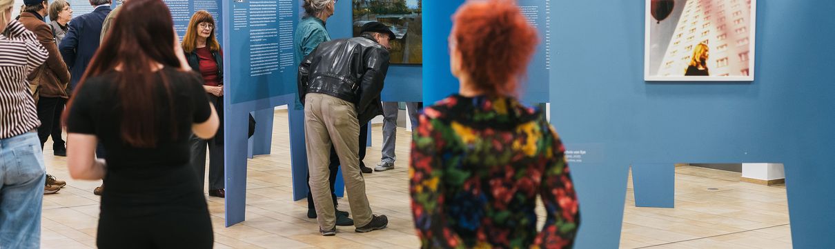 Menschen schauen sich Bilder in einer Ausstellung an.