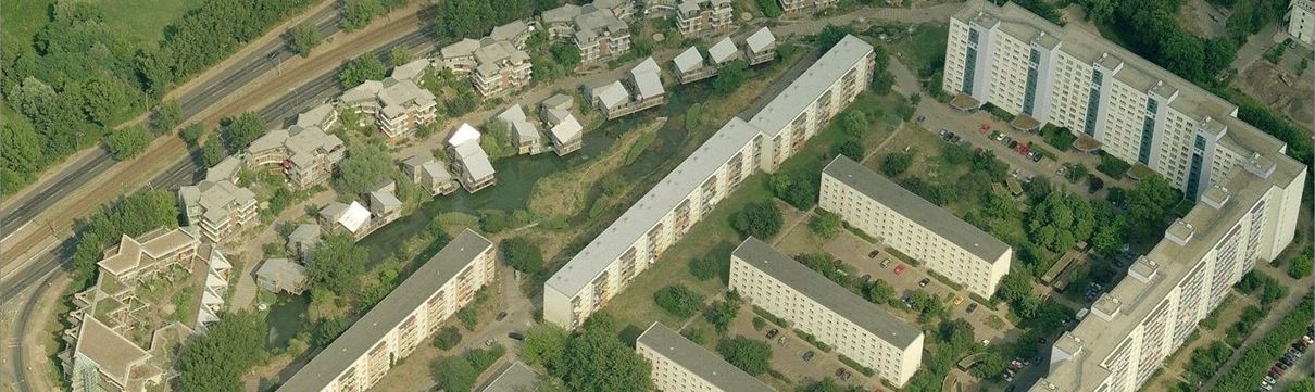 Luftbild einer Serie gleichförmiger Gebäude, die sich an einer Schnellstraße entlangziehen.