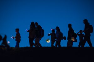 Laternenumzug im Volkspark Potsdam Mehrere Menschen unterschiedlichen Alters laufen im Dunkeln mit Laternen