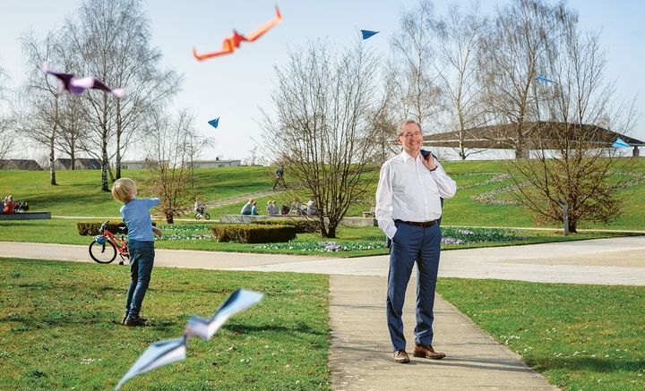 Matthias Platz, rechts, steht im Volkspark und lächelt, links neben ihm lässt ein kleiner Junge Papierflieger steigen.
