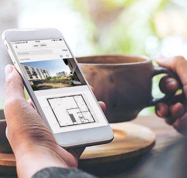 Hand hält Smartphone, um Wohnungsangebote anzusehen