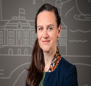 Porträtbild Frau mit langen, dunklen Haaren und blauem Blazer