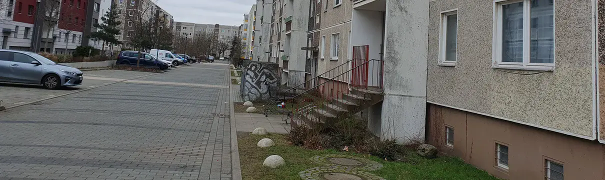 Straßenperspektive mit grünem Vorgarten und Wohnhaus