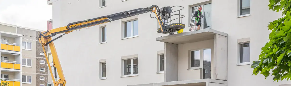Bausstellenfahrzeuge und große Balkonbetonteile, die an der neuen Fassade im Hetha-Thiele-Weg montiert werden.