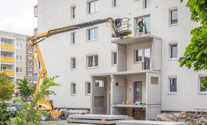 Bausstellenfahrzeuge und große Balkonbetonteile, die an der neuen Fassade im Hetha-Thiele-Weg montiert werden.