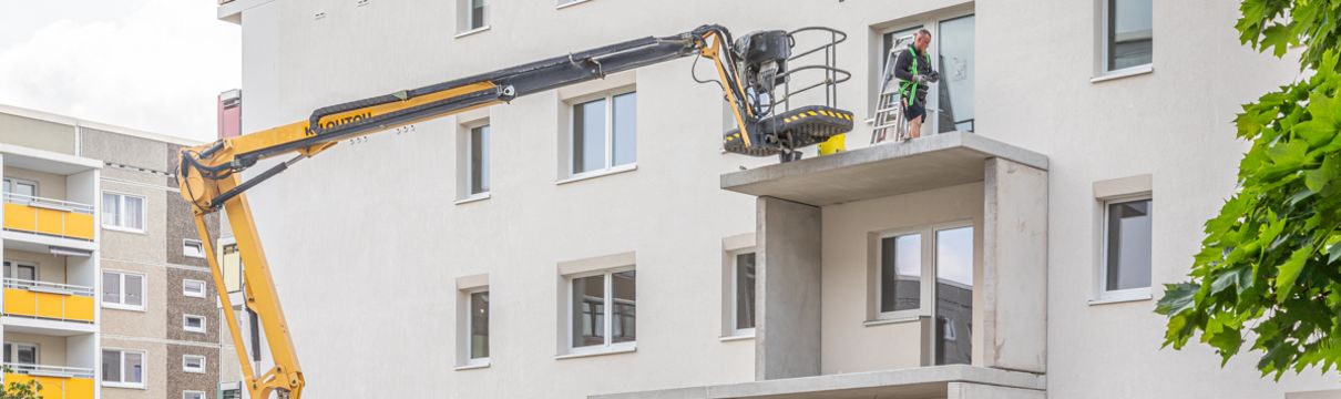 Bausstellenfahrzeuge und große Balkonbetonteile, die an der neuen Fassade im Hetha-Thiele-Weg montiert werden.