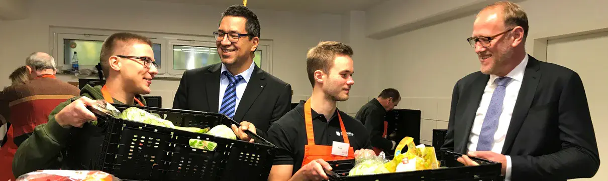 Die Geschäftsführer der ProPotsdam stehen zusammen mit zwei Jugendlichen vor Körben mit Gemüse und Nahrungsmitteln.