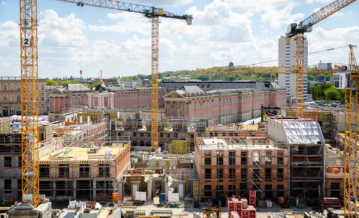 Dicht bebauter Baugrund mit Gerüsten und Kränen. Im Hintergrund sieht man das Stadtschloss, dem Sitz des Potsdamer Landtags