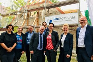 Ein Gruppenbild mit der Geschäftsführung der ProPotsdam vor einem mit einem Baugerüst verkleideten Haus.