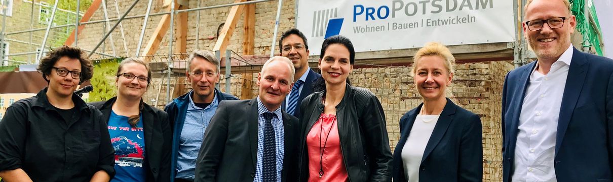 Ein Gruppenbild mit der Geschäftsführung der ProPotsdam vor einem mit einem Baugerüst verkleideten Haus.