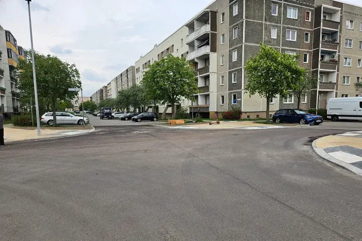 Frisch asphaltierte Kreuzung in Potsdam-Drewitz. Neue Straßenmarkierungen, Bordsteine und Stellflächen sind zu sehen.