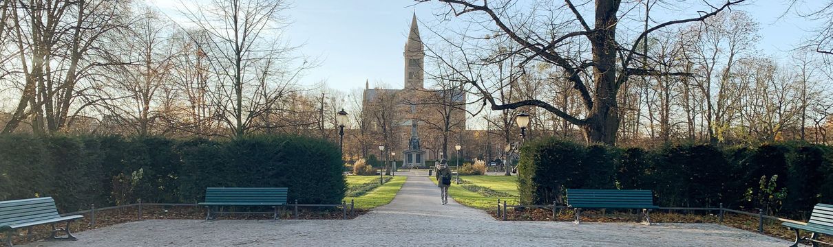 Ein Platz mit einem Fußweg, Bänken, Laternen und einer Kirche