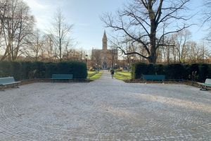 Ein Platz mit einem Fußweg, Bänken, Laternen und einer Kirche